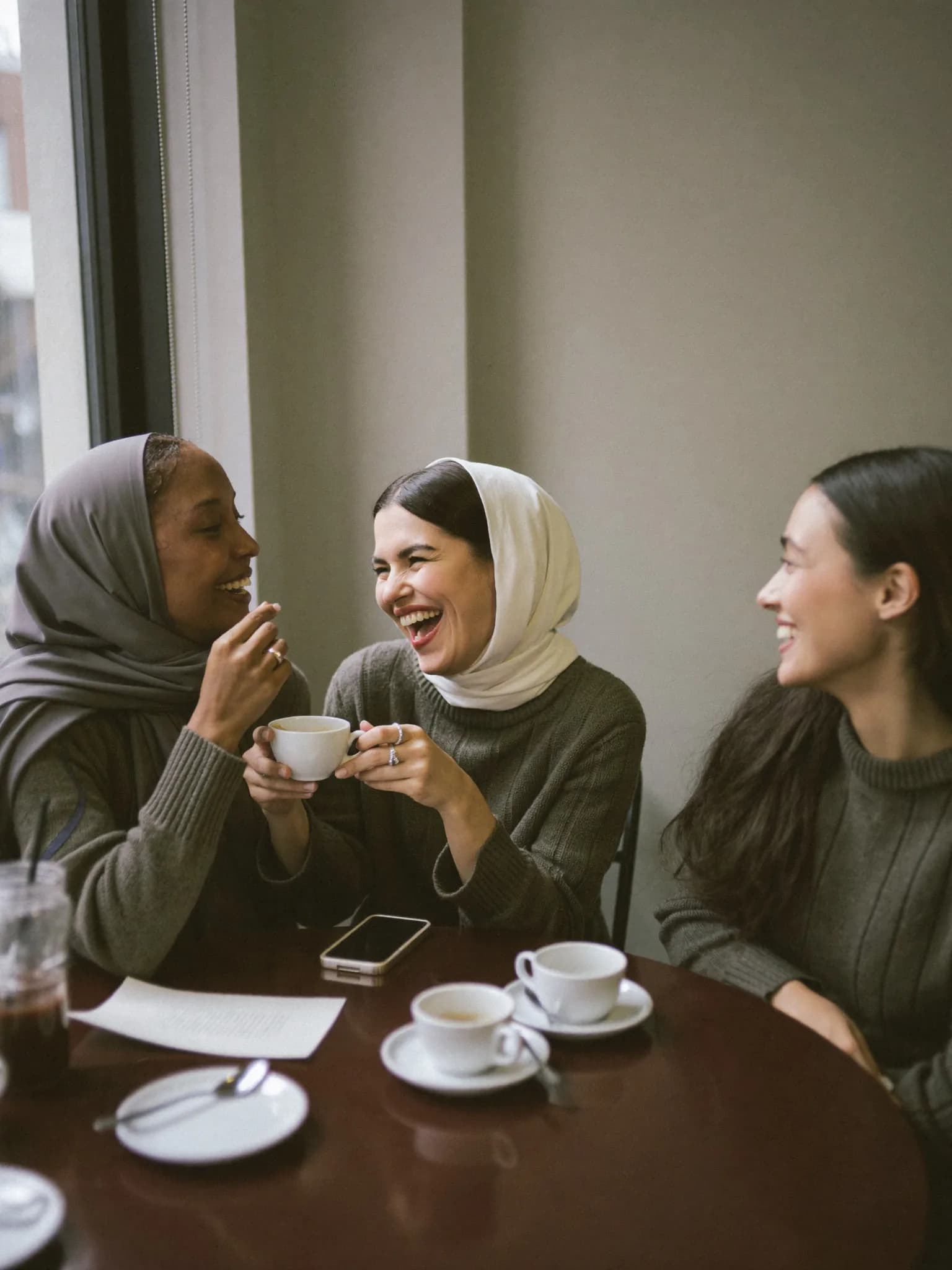 Three women talking warmly together over coffee
