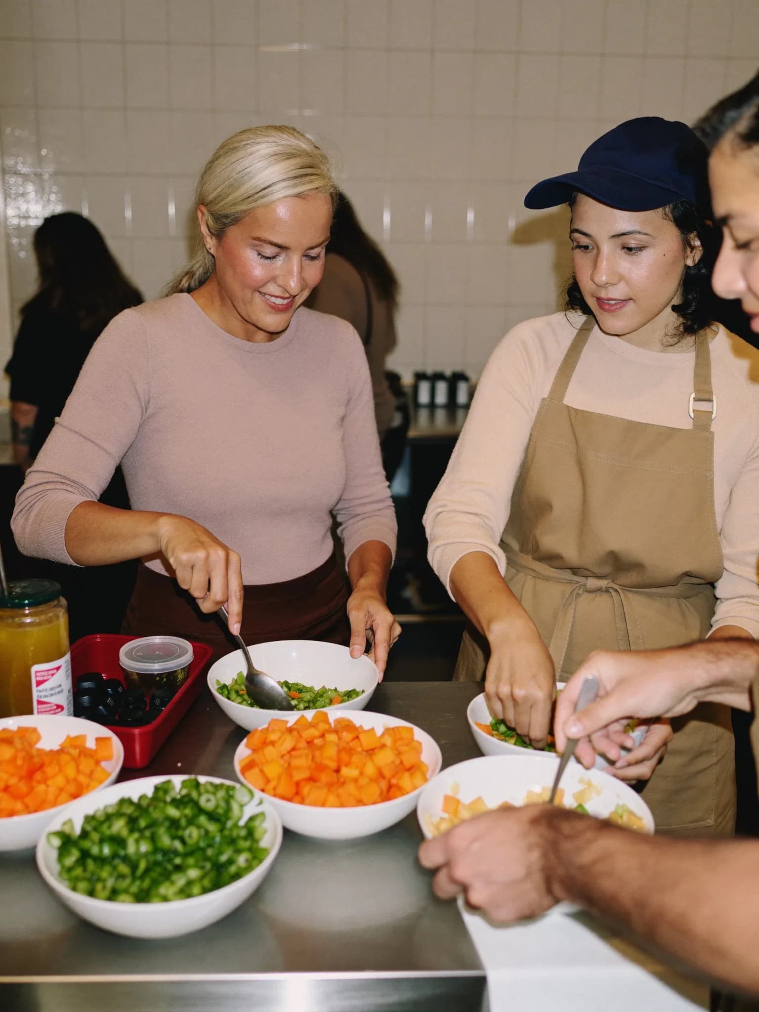 Women arranging chopped vegetables into bowls in a community kitchen
