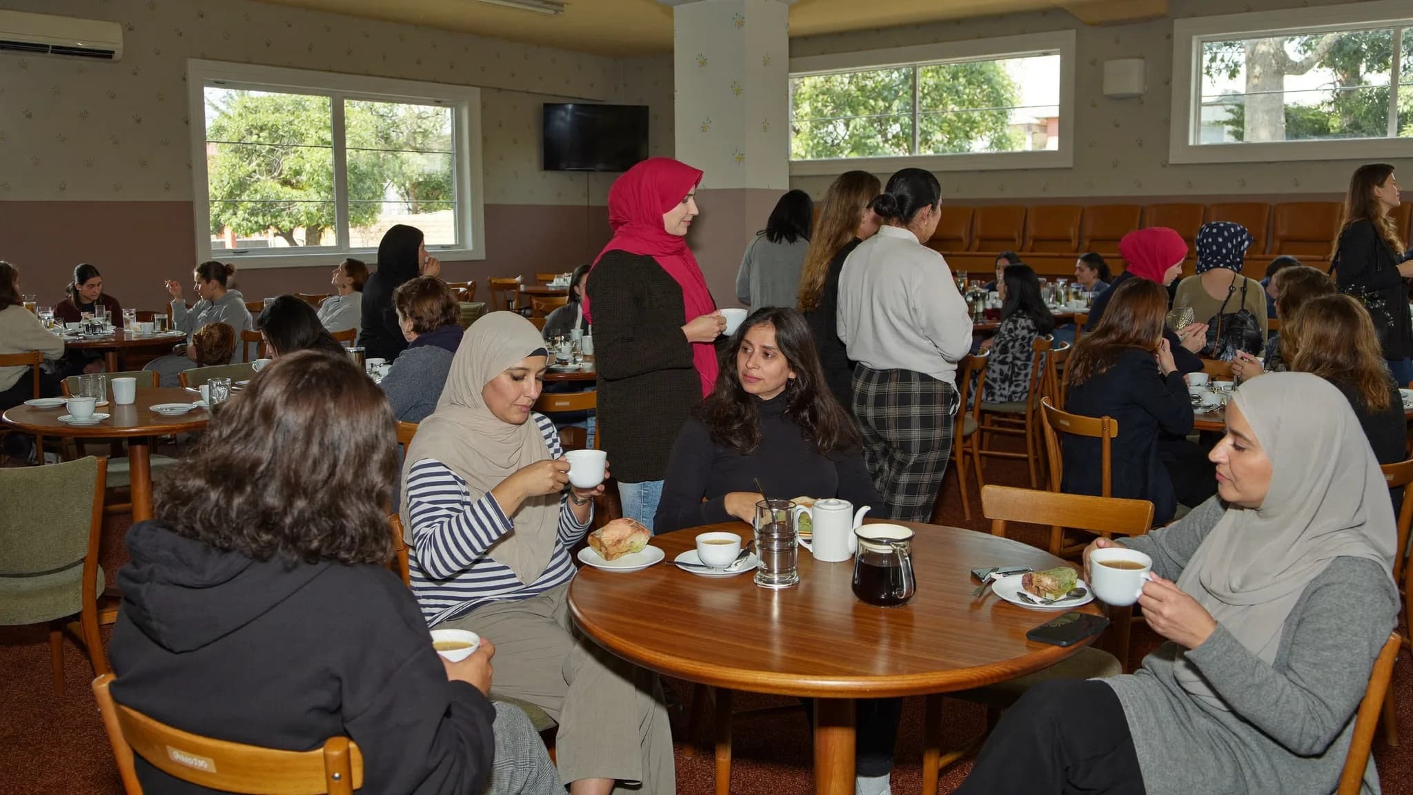 Women talking in small groups over tea at a community coffee morning