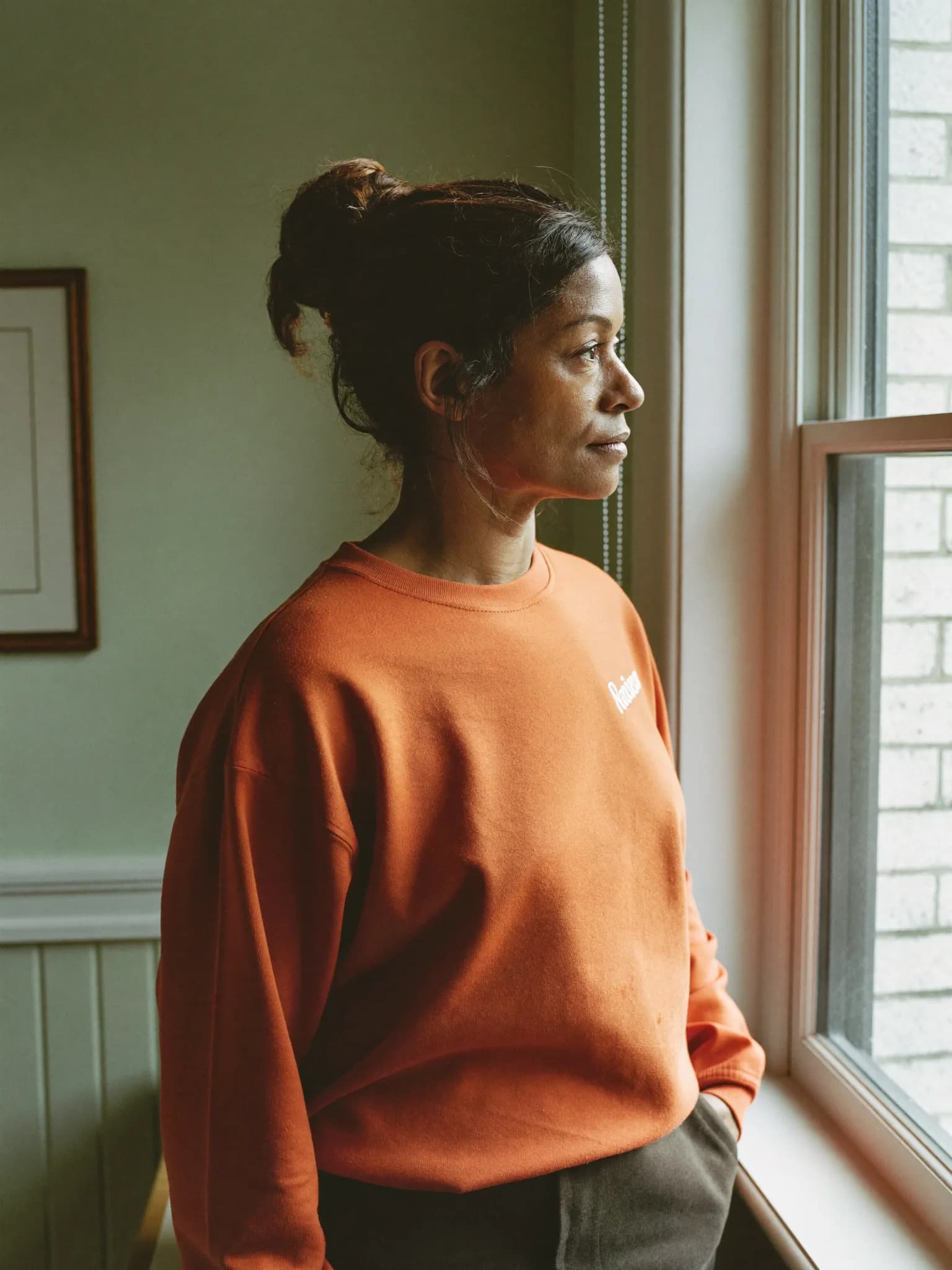 A woman looking out of a window with a thoughtful expression